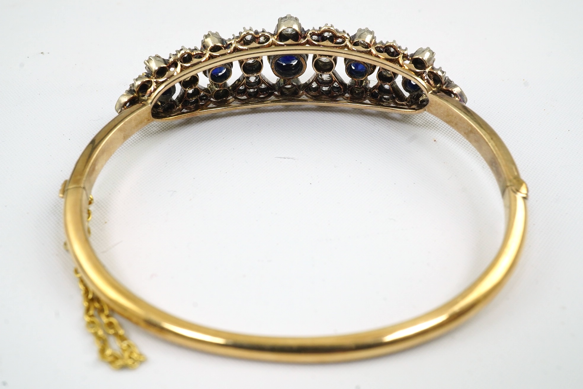 A late Victorian gold, sapphire and diamond cluster hinged bangle